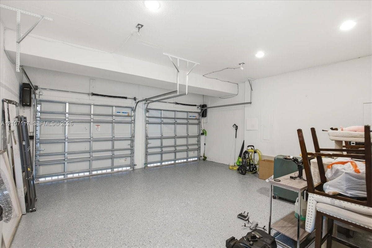 7863 NW 111th Court, Doral, FL 33178 Two-car garage featuring dual overhead metal doors, neutral wall finish, recessed lighting, and durable flecked-epoxy flooring