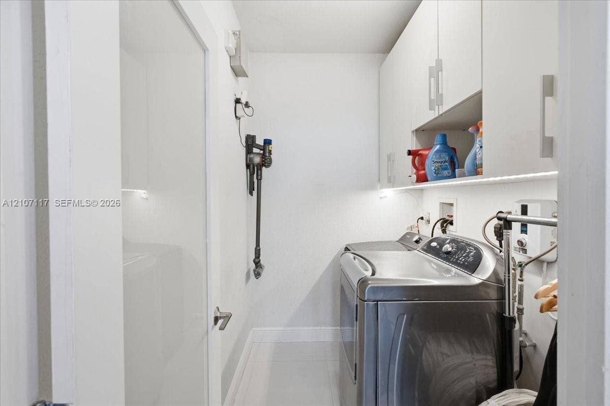 7863 NW 111th Court, Doral, FL 33178 Laundry room featuring flat-panel upper cabinetry, under-cabinet task lighting, and neutral tile flooring