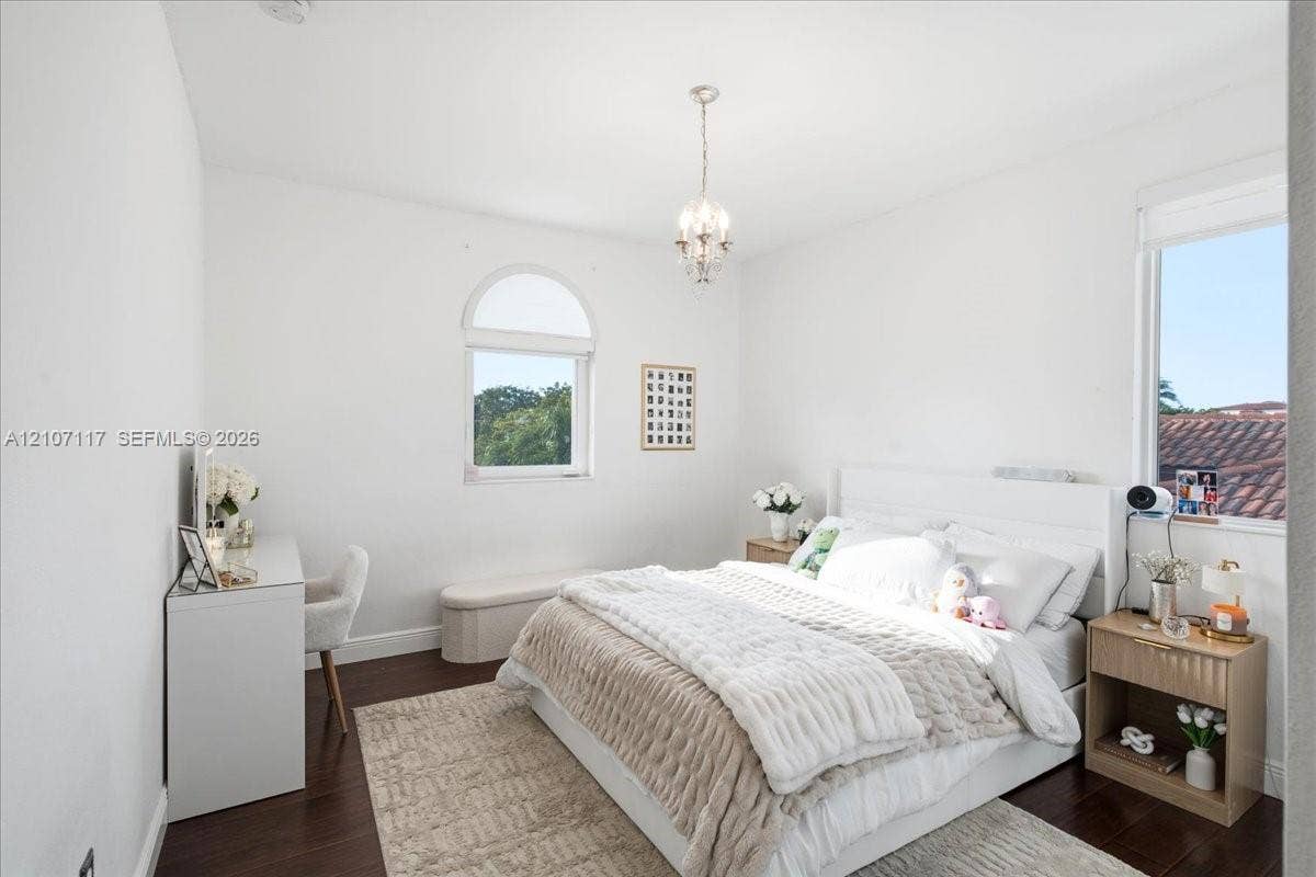 7863 NW 111th Court, Doral, FL 33178 Room featuring wood-finish flooring, an arched window, and a central crystal-style chandelier