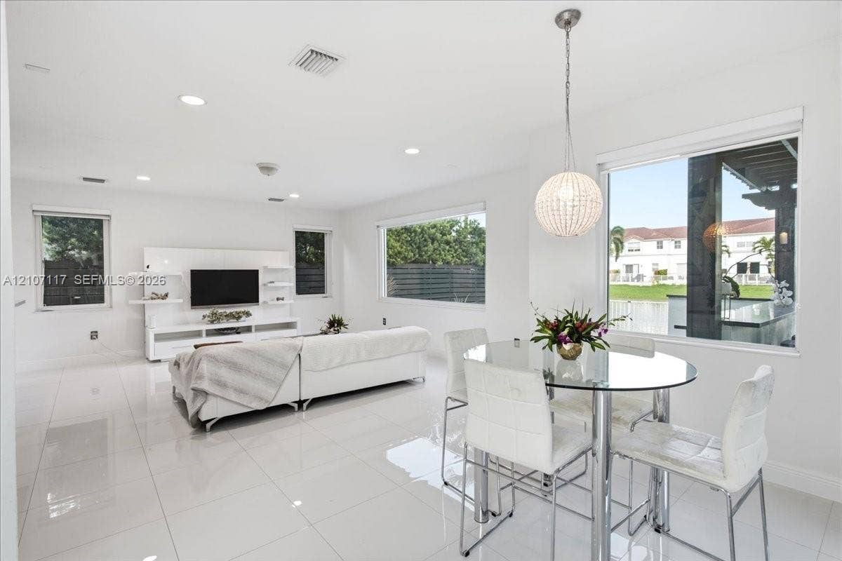 7863 NW 111th Court, Doral, FL 33178 Open-concept interior featuring large-format tile flooring, recessed lighting, a built-in media console, and a spherical crystal pendant light