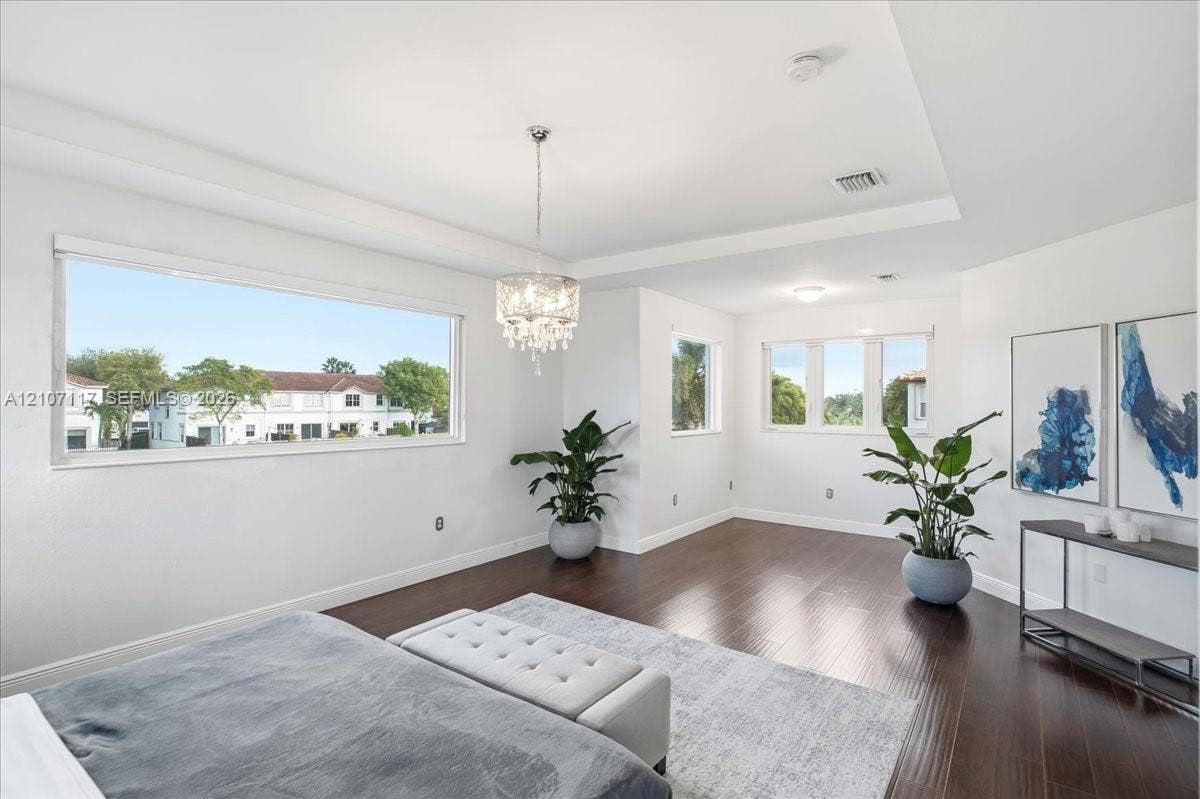 7863 NW 111th Court, Doral, FL 33178 Spacious room featuring wood-finish flooring, recessed tray ceiling, large picture windows, and a crystal chandelier