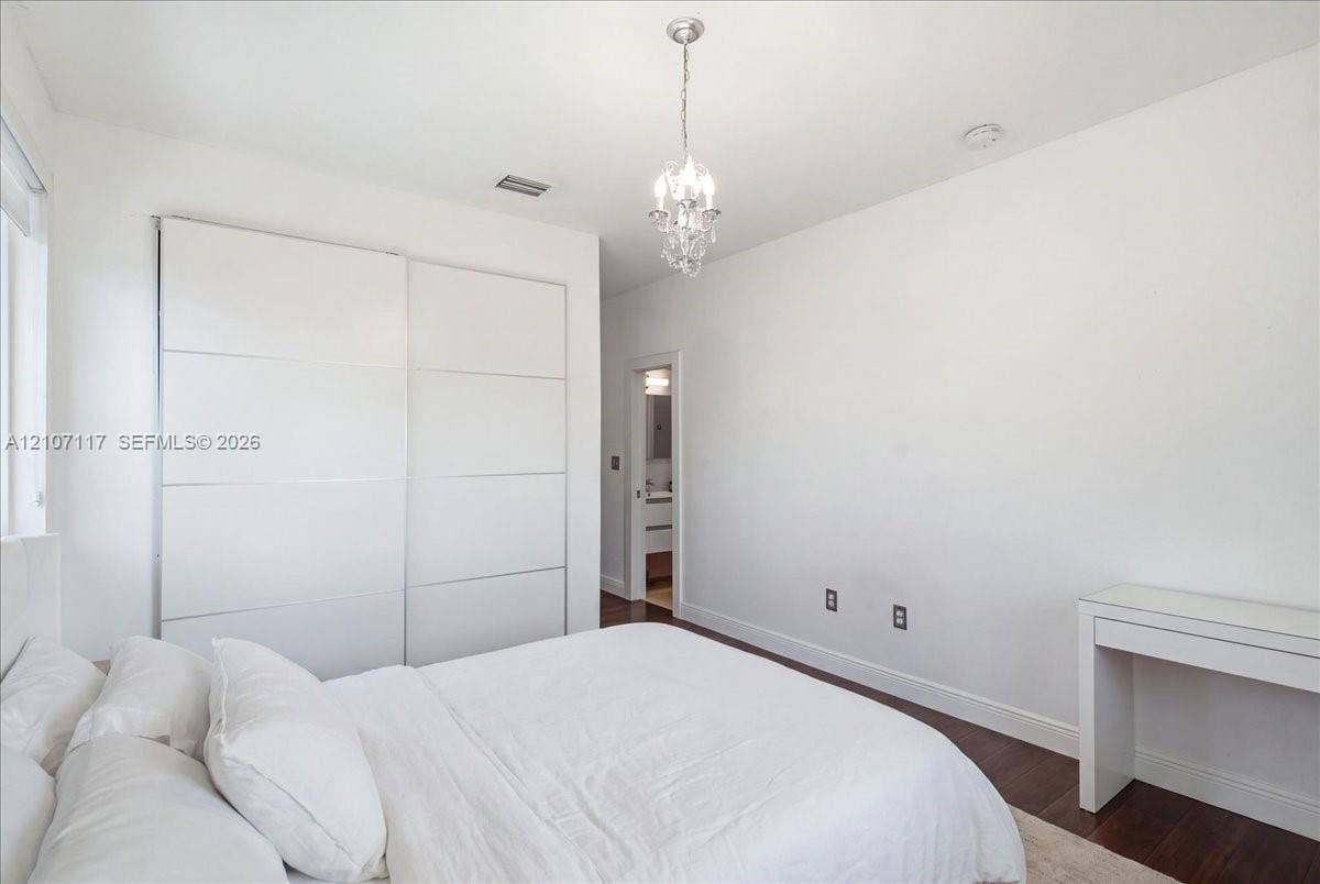 7863 NW 111th Court, Doral, FL 33178 Room featuring dark wood-finish flooring, floor-to-ceiling built-in sliding door wardrobe, and a crystal chandelier