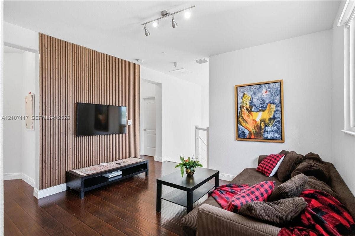 7863 NW 111th Court, Doral, FL 33178 Vertical wood slat accent wall, dark-toned wood-finish flooring, and adjustable multi-bulb track lighting