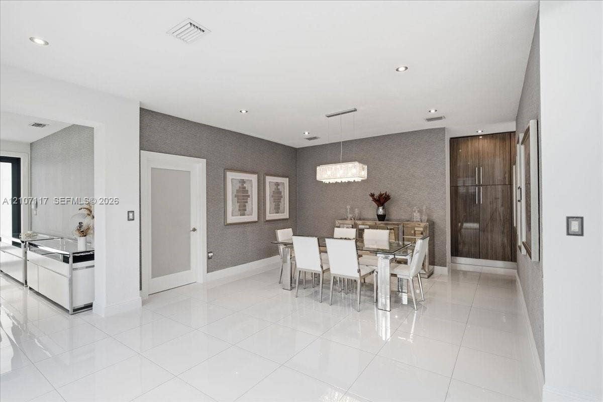 7863 NW 111th Court, Doral, FL 33178 Open-concept interior featuring large-format polished tile flooring, textured wall coverings, a modern rectangular chandelier, and built-in full-height wood-finish cabinetry