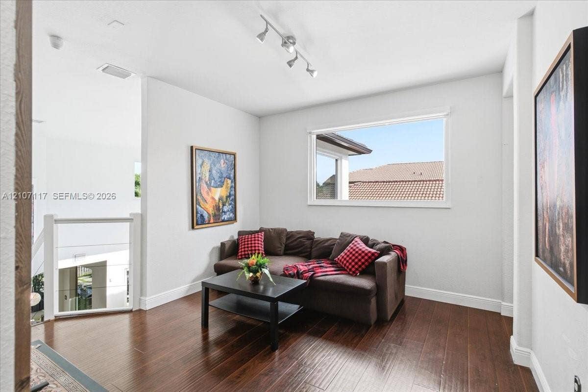 7863 NW 111th Court, Doral, FL 33178 Wood-finish flooring, white walls, multi-directional track lighting, and a horizontal window with exterior trim