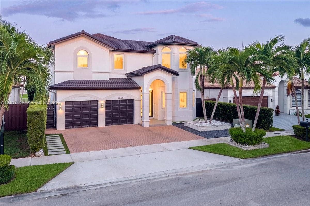 7863 NW 111th Court, Doral, FL 33178 Two-story Mediterranean-style exterior featuring a tile roof, arched entryway, stucco facade, and an attached two-car garage with a paved driveway
