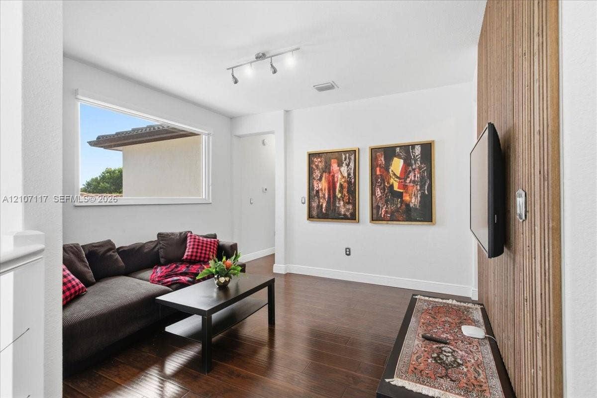 7863 NW 111th Court, Doral, FL 33178 Interior space featuring wood-finish flooring, a decorative vertical slat wood wall, and a multi-bulb track lighting fixture