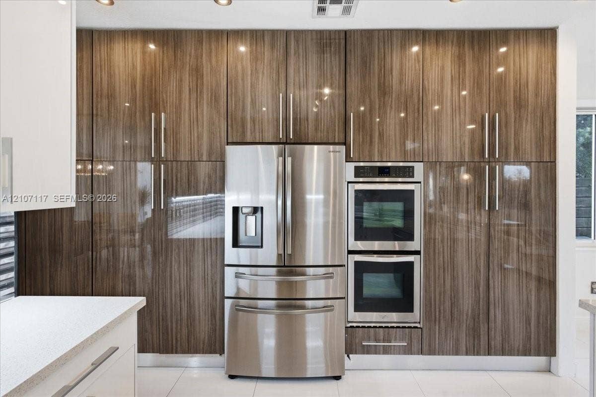 7863 NW 111th Court, Doral, FL 33178 Full-height high-gloss wood-finish cabinetry, stainless steel French door refrigerator, built-in double wall oven, and light-toned solid surface countertops