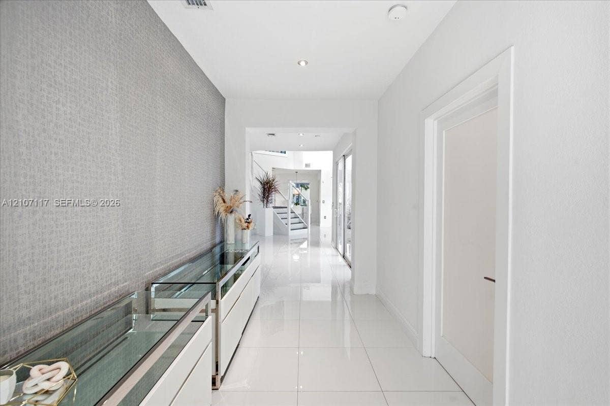 7863 NW 111th Court, Doral, FL 33178 Hallway featuring polished white tile flooring, recessed lighting, and a textured grey accent wall