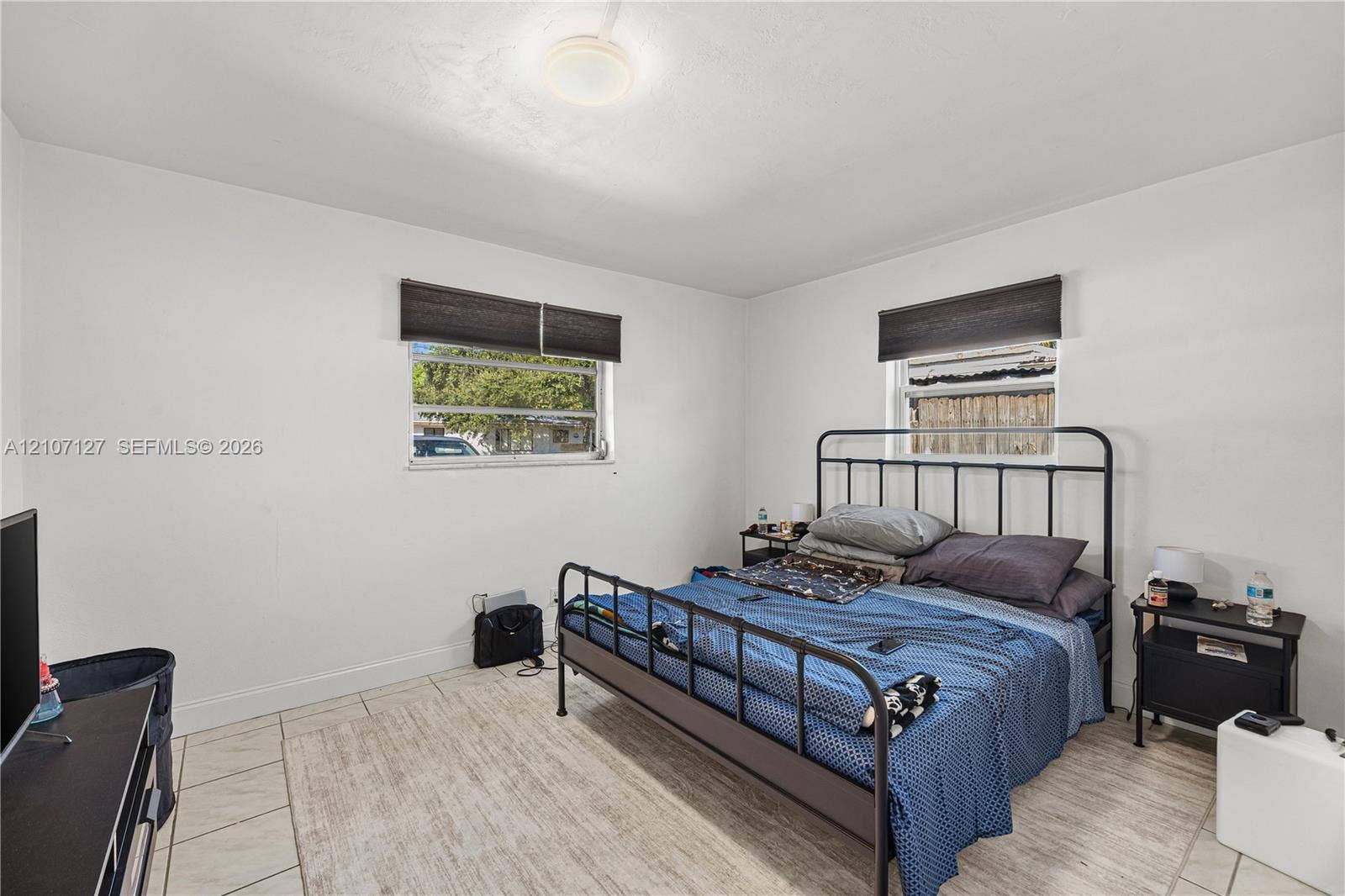 Neutral wall tones, ceramic tile flooring, and dual windows with dark-finish shades