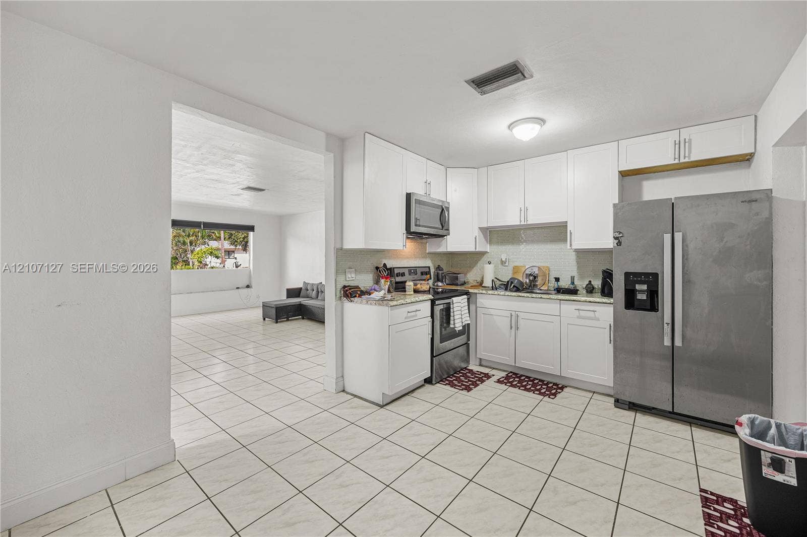 Kitchen featuring white cabinetry, stone-finish countertops, stainless steel appliances, and tiled flooring