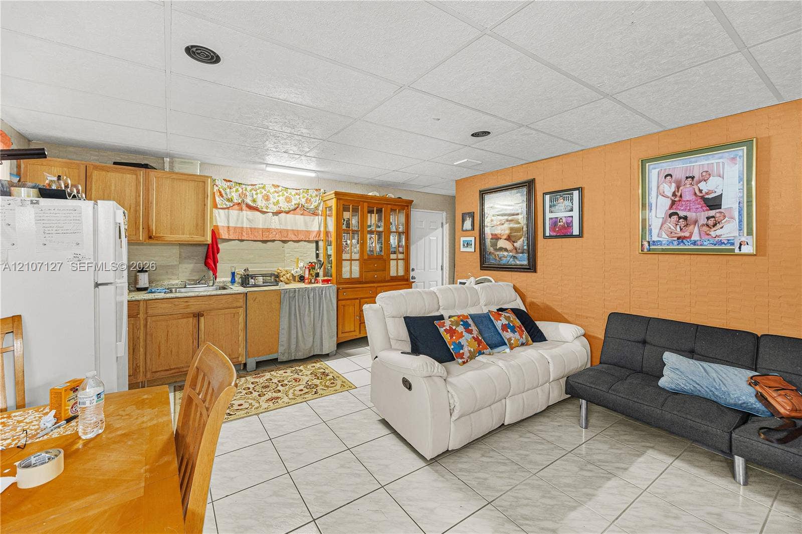 Kitchenette featuring wood-finish cabinetry, tile flooring, and a drop ceiling