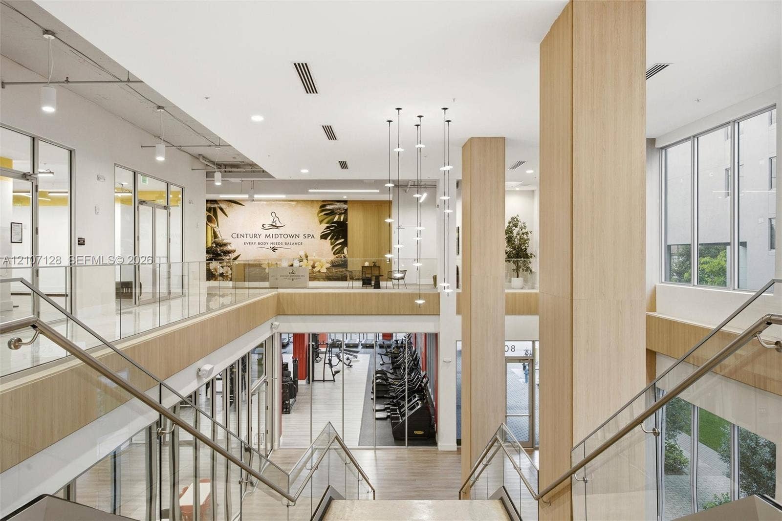 7875 NW 107th Avenue, #802, Doral, Doral, FL 33178 Multi-level interior space featuring wood-finish paneling, floor-to-ceiling glass partitions, a glass-panel staircase railing, large windows, and a multi-pendant lighting fixture