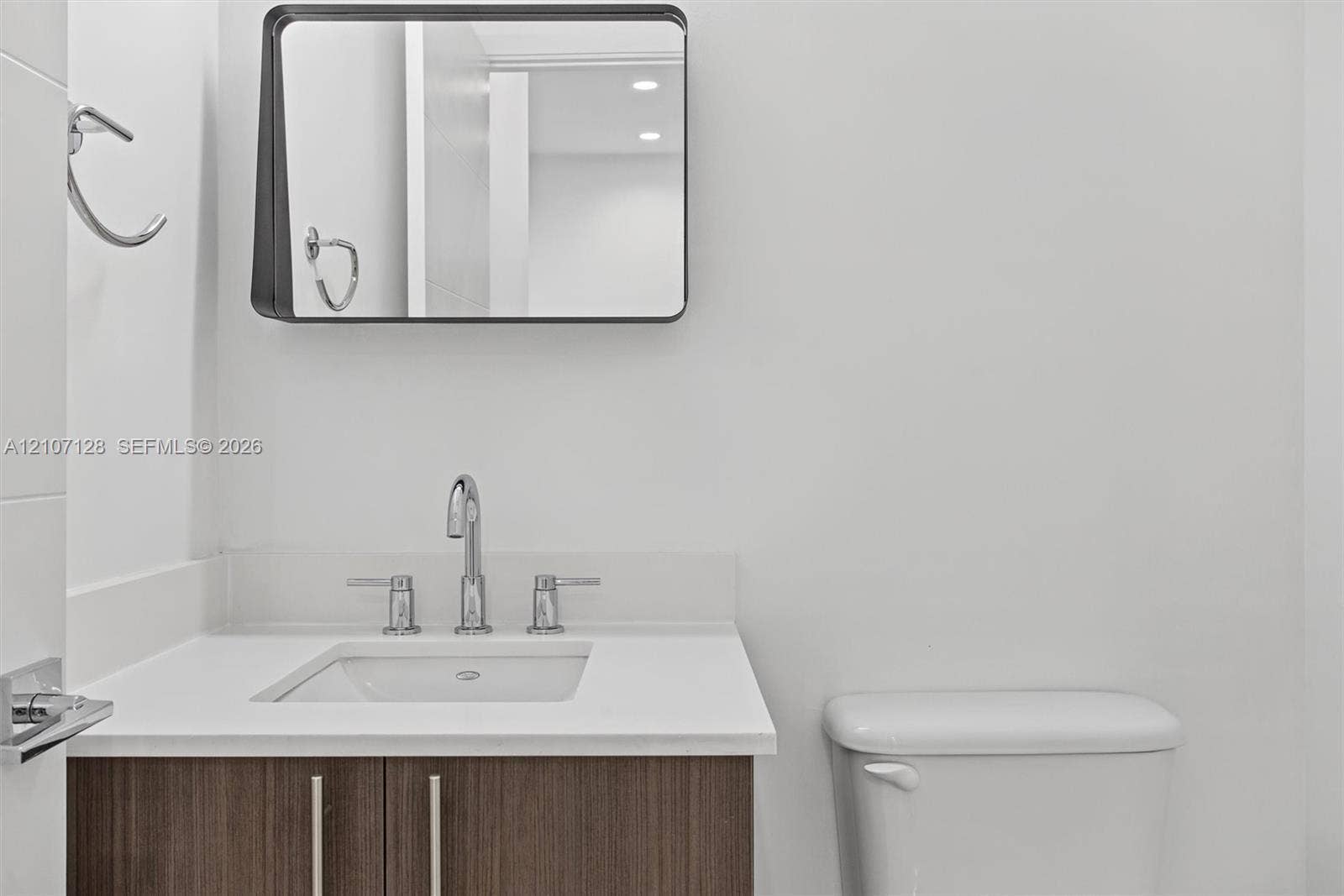 7875 NW 107th Avenue, #802, Doral, Doral, FL 33178 Powder room with wood-finish cabinetry, stone-surface countertop, rectangular undermount sink, chrome widespread faucet, and a wall-mounted mirror