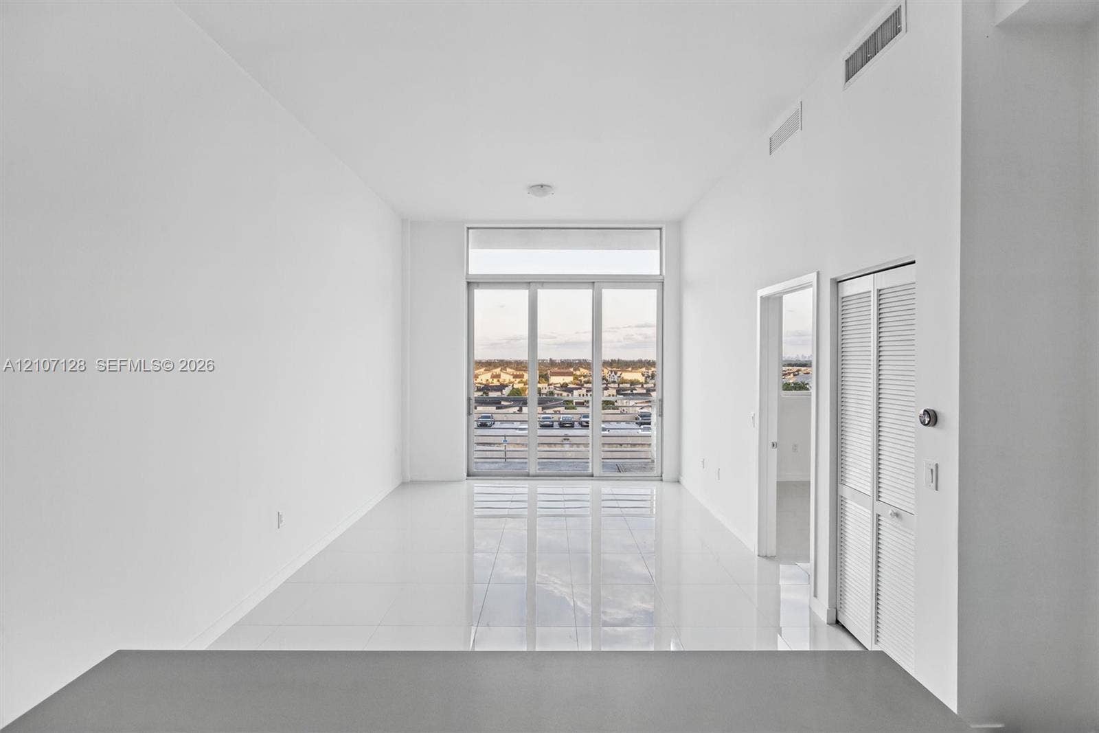 7875 NW 107th Avenue, #802, Doral, Doral, FL 33178 Living area features high ceilings & full-height glass sliding doors, polished tile flooring, and louvered bifold closet doors