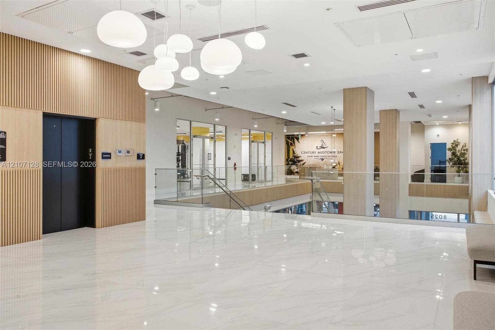 7875 NW 107th Avenue, #802, Doral, Doral, FL 33178 Polished stone flooring, vertical wood-slat wall paneling, multi-globe pendant lighting, glass panel railings, and recessed ceiling lighting