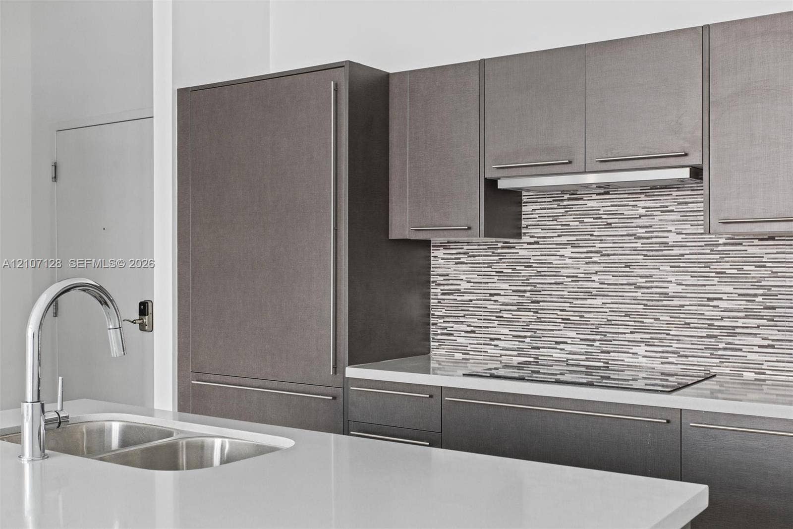 7875 NW 107th Avenue, #802, Doral, Doral, FL 33178 Kitchen featuring flat-panel cabinetry, quartz countertops, horizontal mosaic tile backsplash, integrated Bosch refrigerator, and stainless steel undermount double-basin sink with arched pull-down faucet