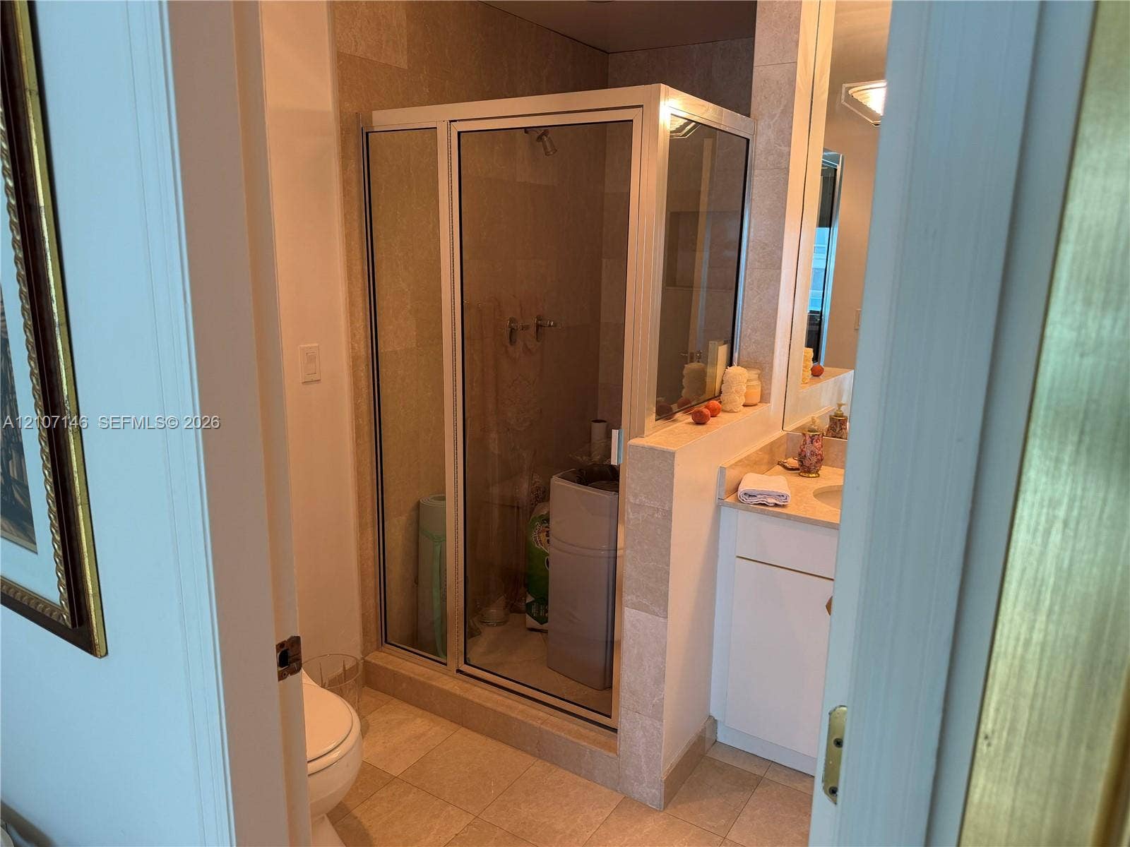 Glass-enclosed shower with metal frame, stone-tile flooring, wall-mounted vanity with solid-surface countertop, and full-width wall mirror