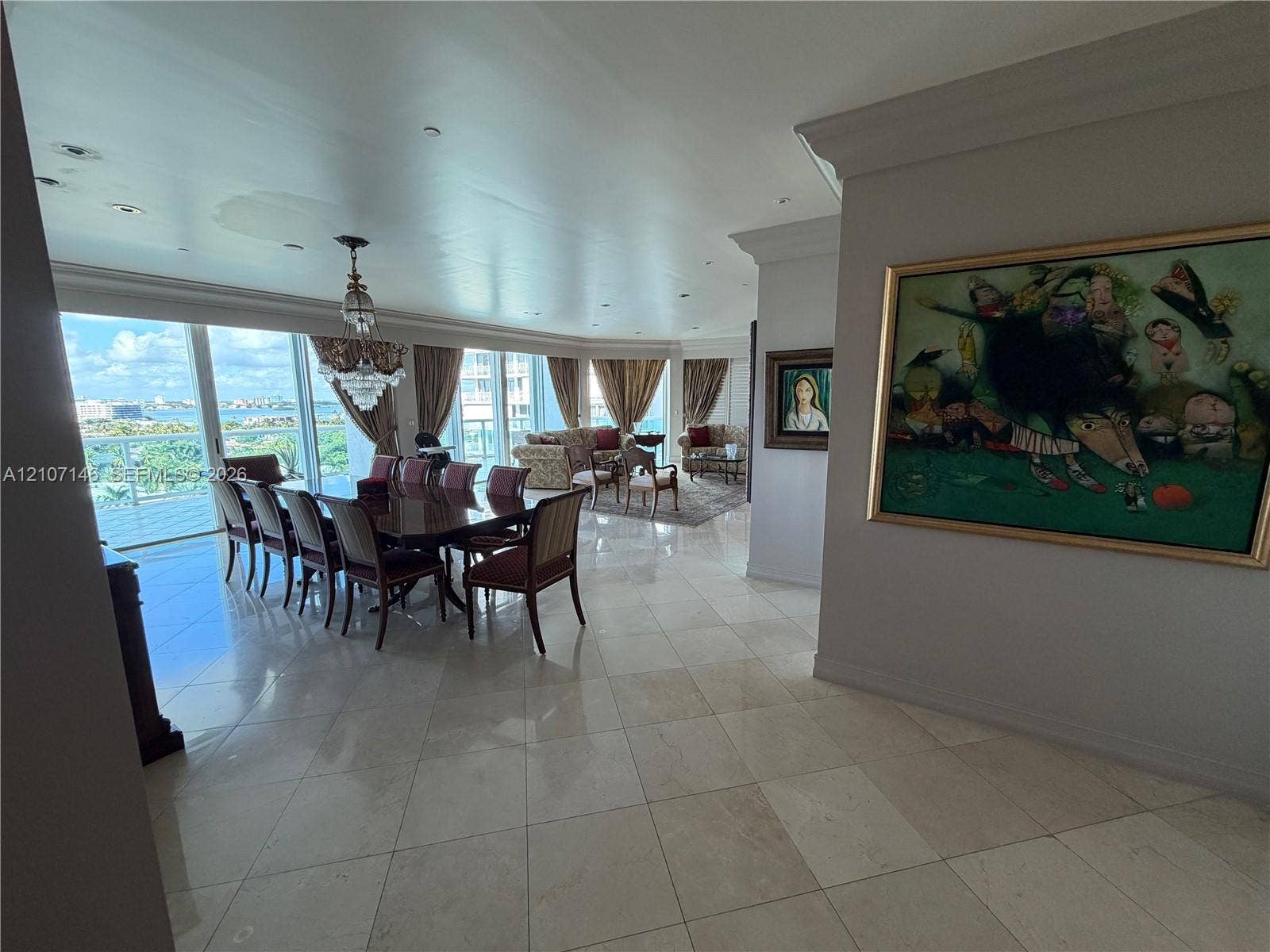 Polished stone flooring, recessed ceiling lighting, crystal chandelier, and floor-to-ceiling glass sliding doors opening to an exterior balcony