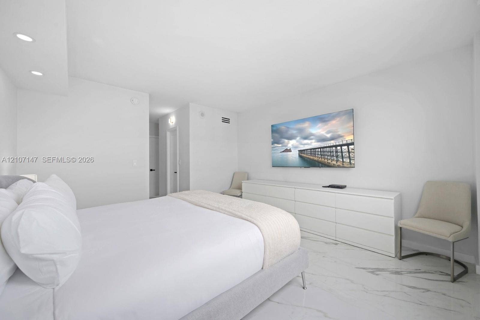 Neutral interior featuring large-format stone-patterned flooring, recessed ceiling lighting, and smooth finish walls