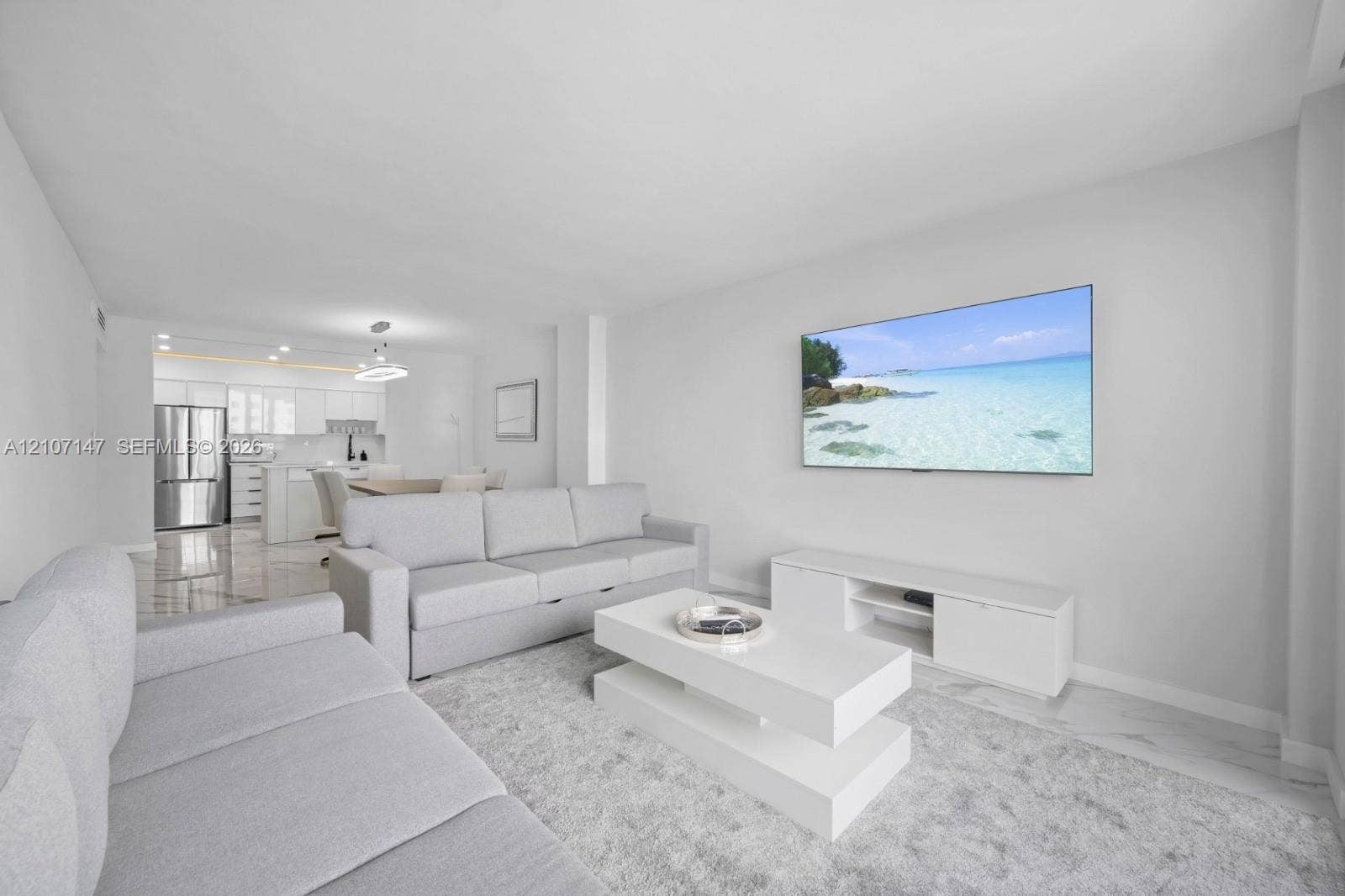 Open-concept area featuring tile flooring, white cabinetry, stainless steel kitchen appliances, and recessed ceiling lighting