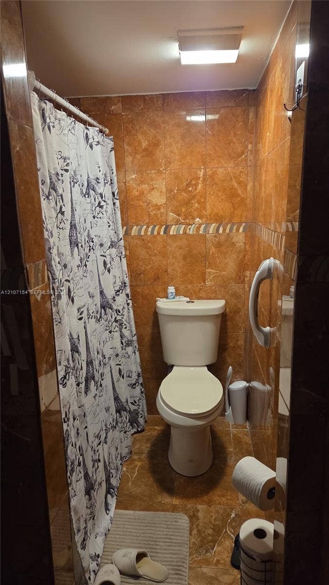 450 Commodore Drive, #311, Plantation, FL 33325 Full-height stone-finish wall tile, decorative mosaic tile inlay, wall-mounted grab bar, and flush-mount ceiling lighting