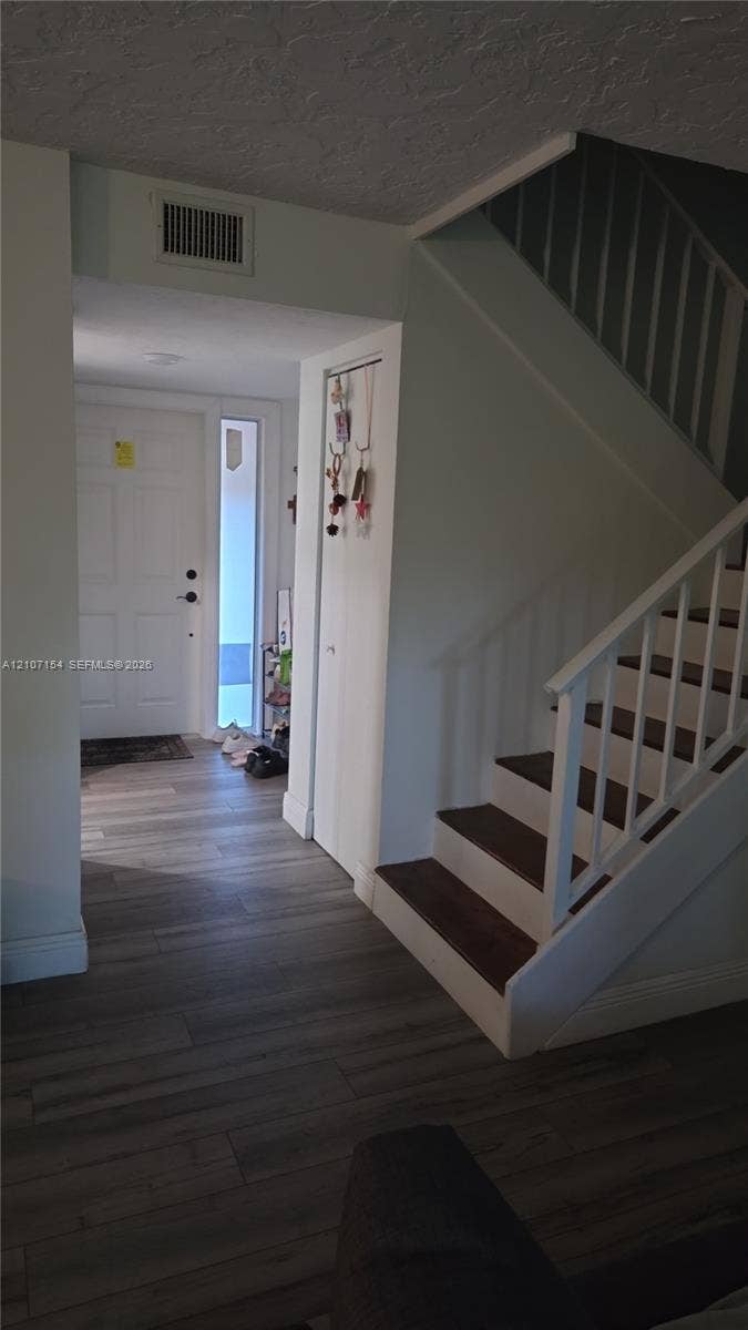 450 Commodore Drive, #311, Plantation, FL 33325 Entryway featuring wood-finish flooring, a white paneled front door with a side light window, and a staircase with white balusters and dark-toned treads