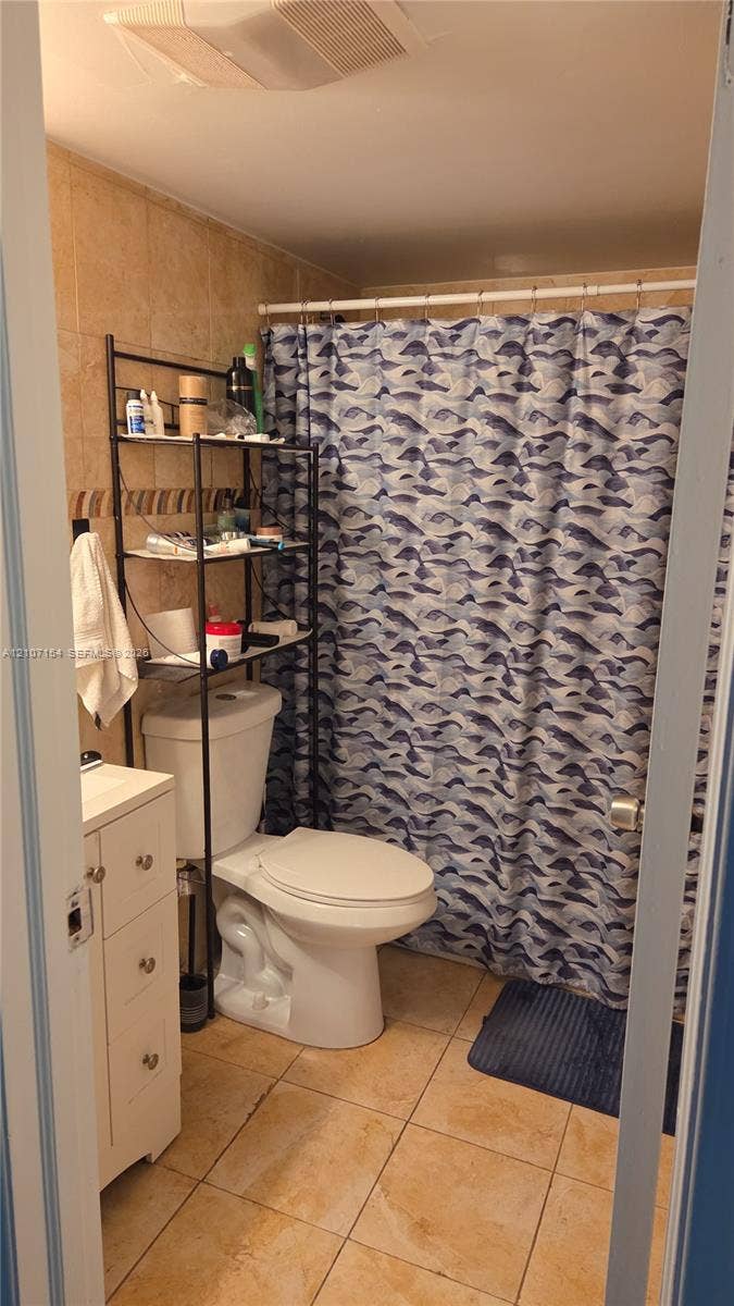 450 Commodore Drive, #311, Plantation, FL 33325 Bathroom featuring light-toned ceramic floor tiling, wall-mounted shower enclosure, white vanity cabinet, and neutral wall tile surround