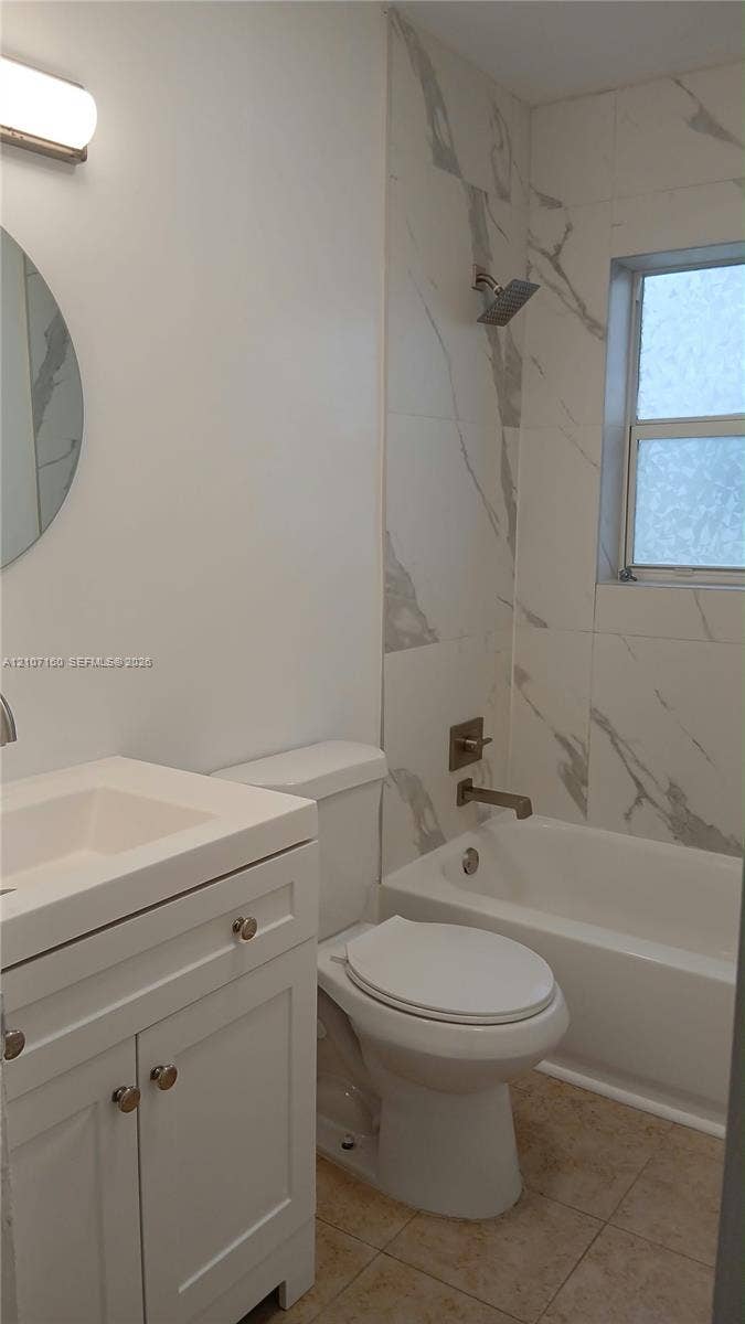 325 NE 2nd Street, #2, Hallandale Beach, Hallandale Beach, FL 33009 Bathroom featuring a white vanity cabinet, rectangular undermount sink, patterned wall tile surrounding the bathtub, and wall-mounted vanity lighting