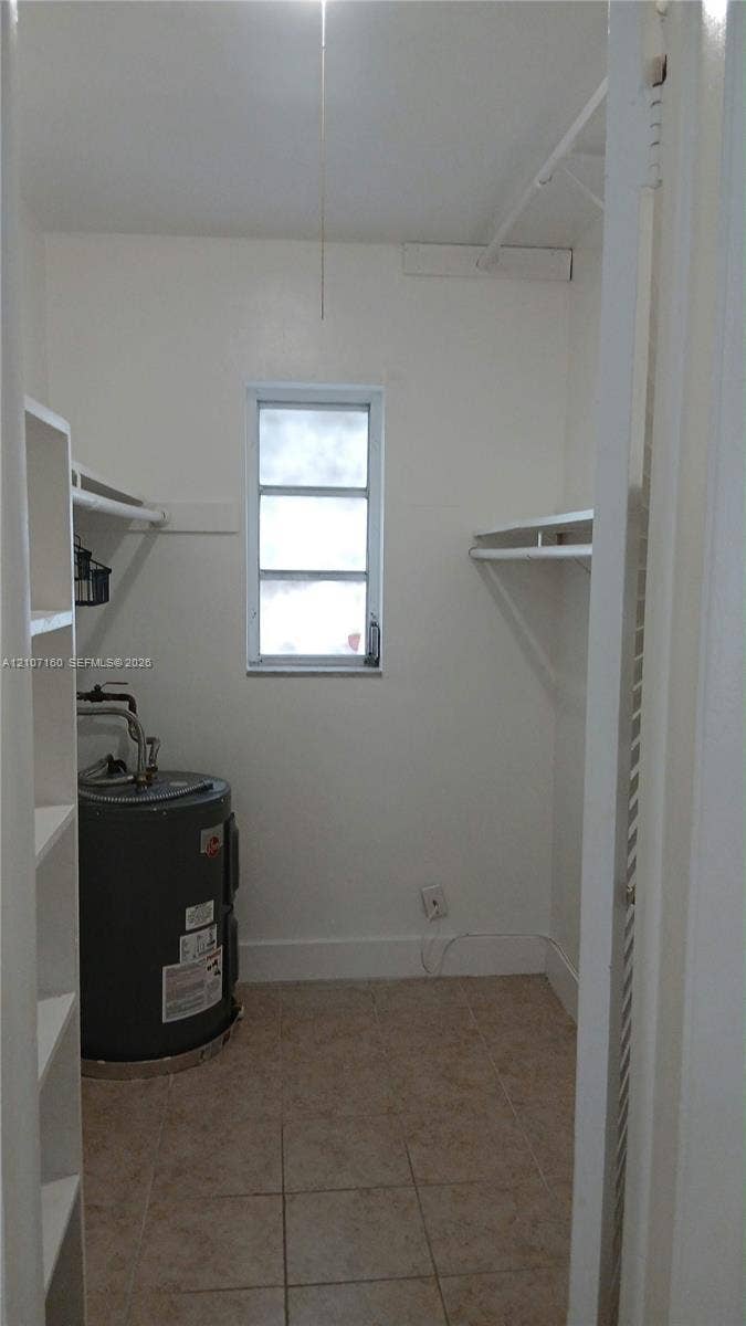 325 NE 2nd Street, #2, Hallandale Beach, Hallandale Beach, FL 33009 Utility room featuring tiled flooring, built-in shelving units, wall-mounted hanging rods, and a single-pane window