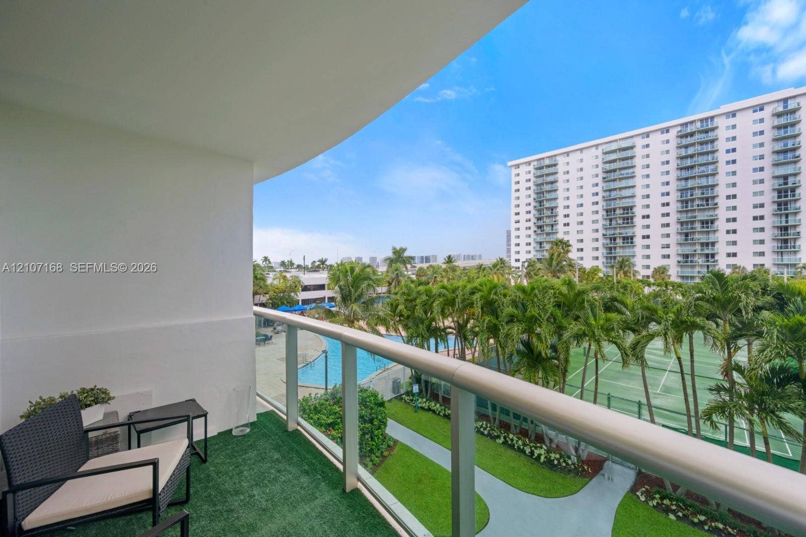 Private balcony featuring glass-panel railings and turf flooring