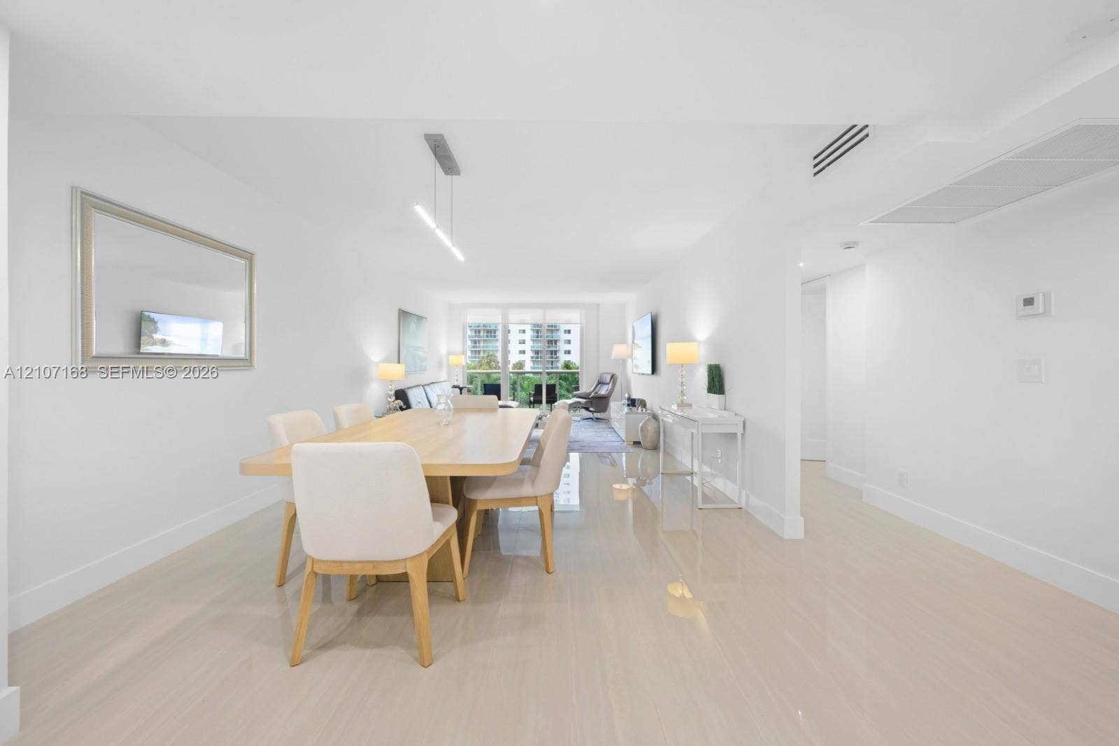 Open-concept interior featuring large-format polished tile flooring, recessed linear lighting, and floor-to-ceiling glass sliders