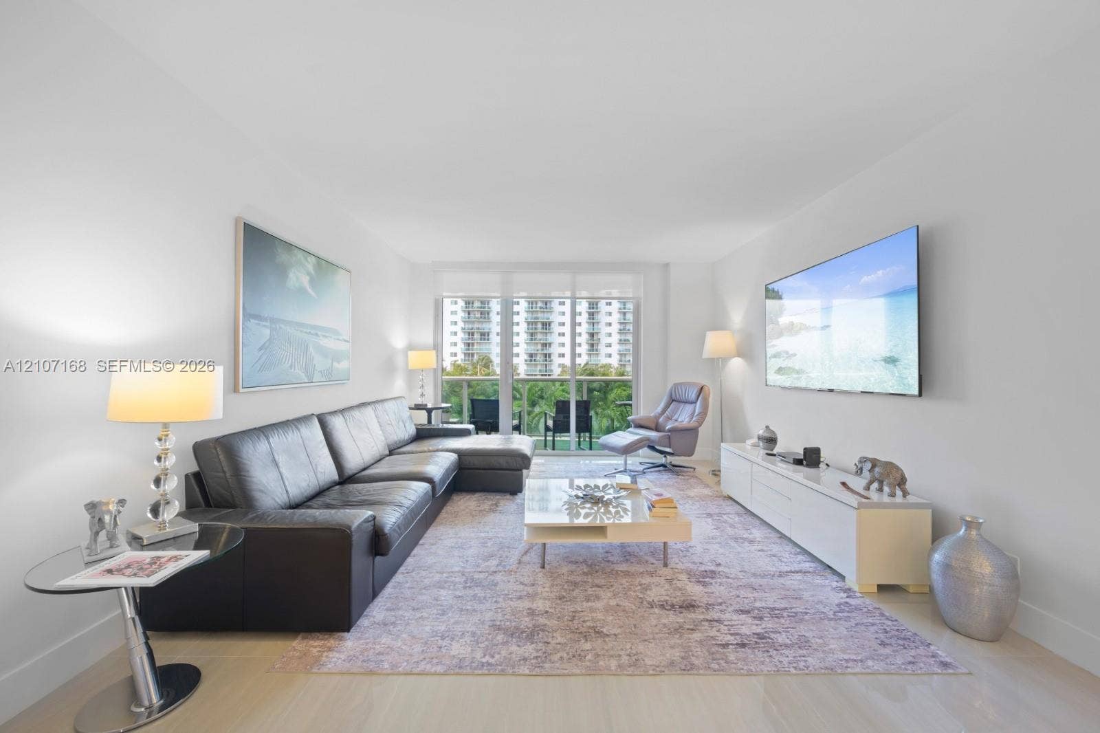Living space featuring wood-finish flooring, floor-to-ceiling glass paneling, and access to a balcony with metal railings