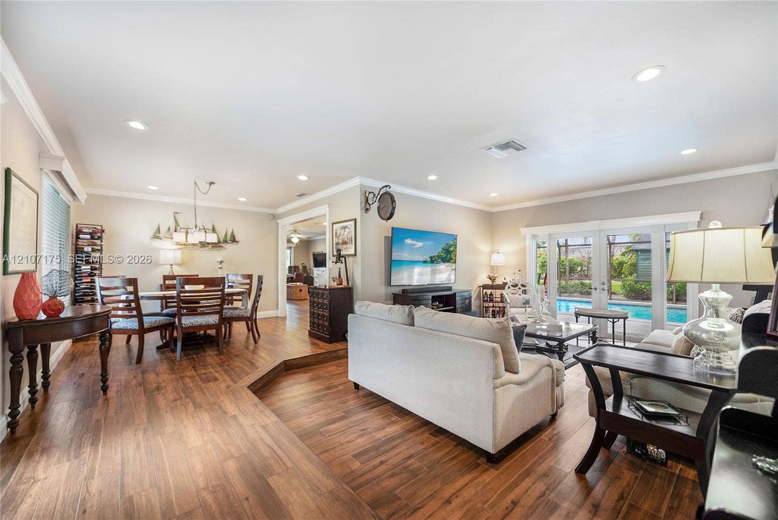 17550 SW 86th Avenue, Palmetto Bay, FL 33157 Open living room with wood-finish tile flooring, recessed lighting, crown molding, and impact glass French doors.