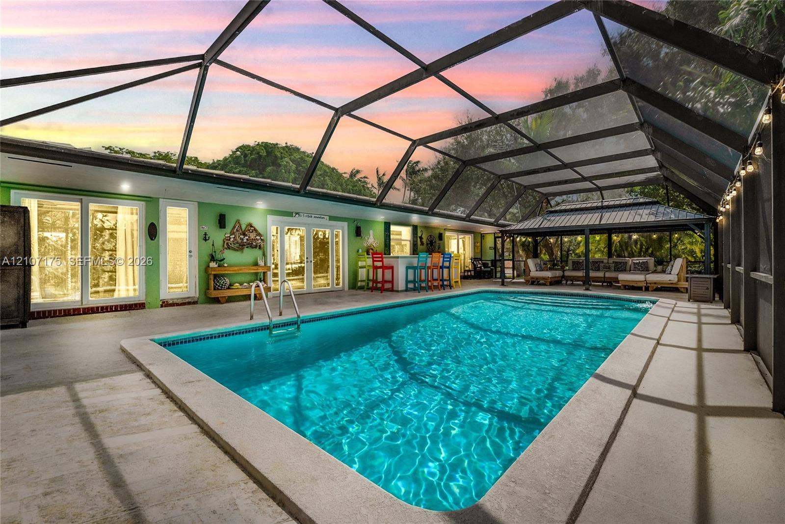 17550 SW 86th Avenue, Palmetto Bay, FL 33157 Screen-enclosed swimming pool featuring a concrete deck, built-in bar area, and hardtop pavilion.