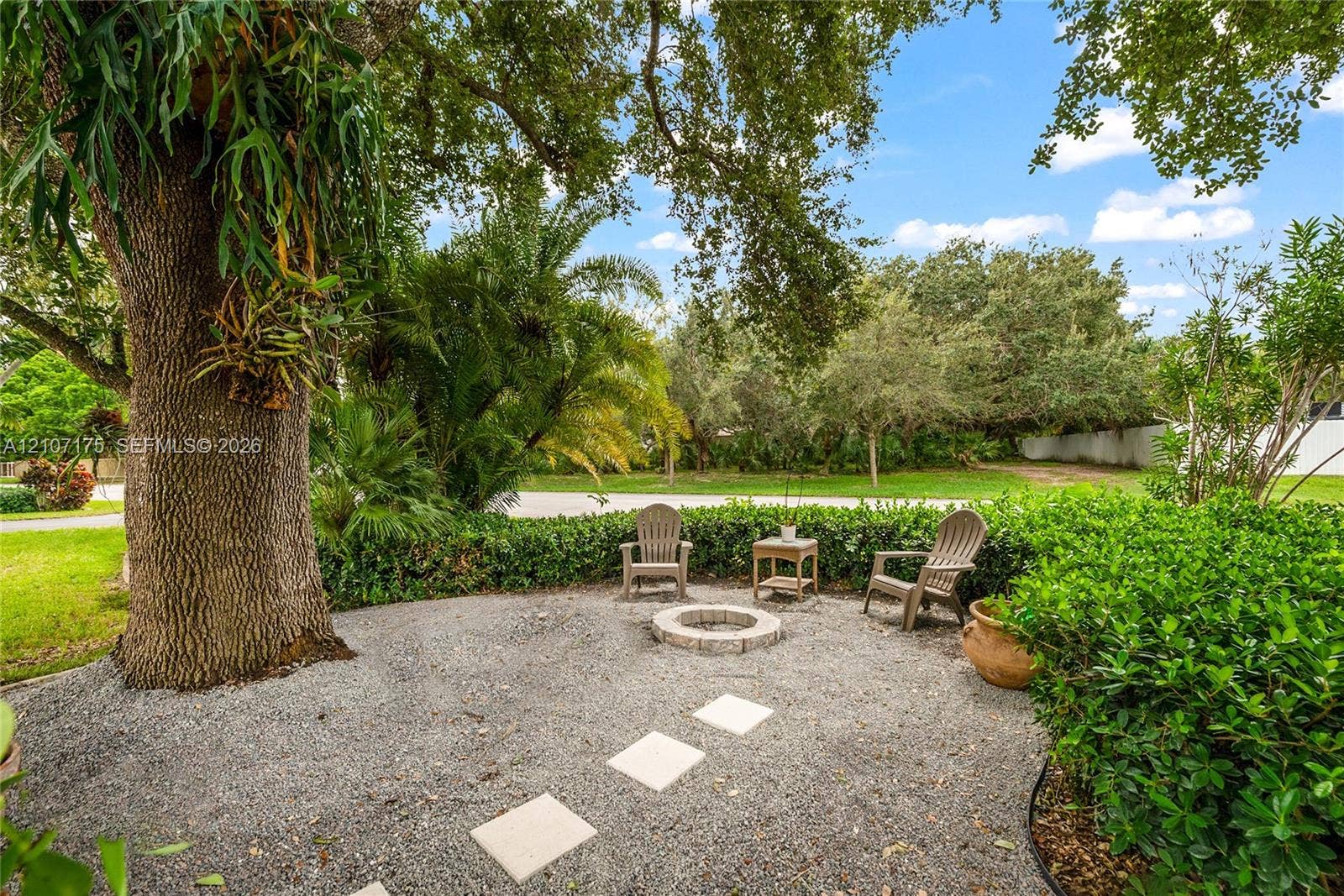 17550 SW 86th Avenue, Palmetto Bay, FL 33157 Outdoor space featuring a gravel courtyard, a circular stone fire pit, paver stones, and mature landscape elements.