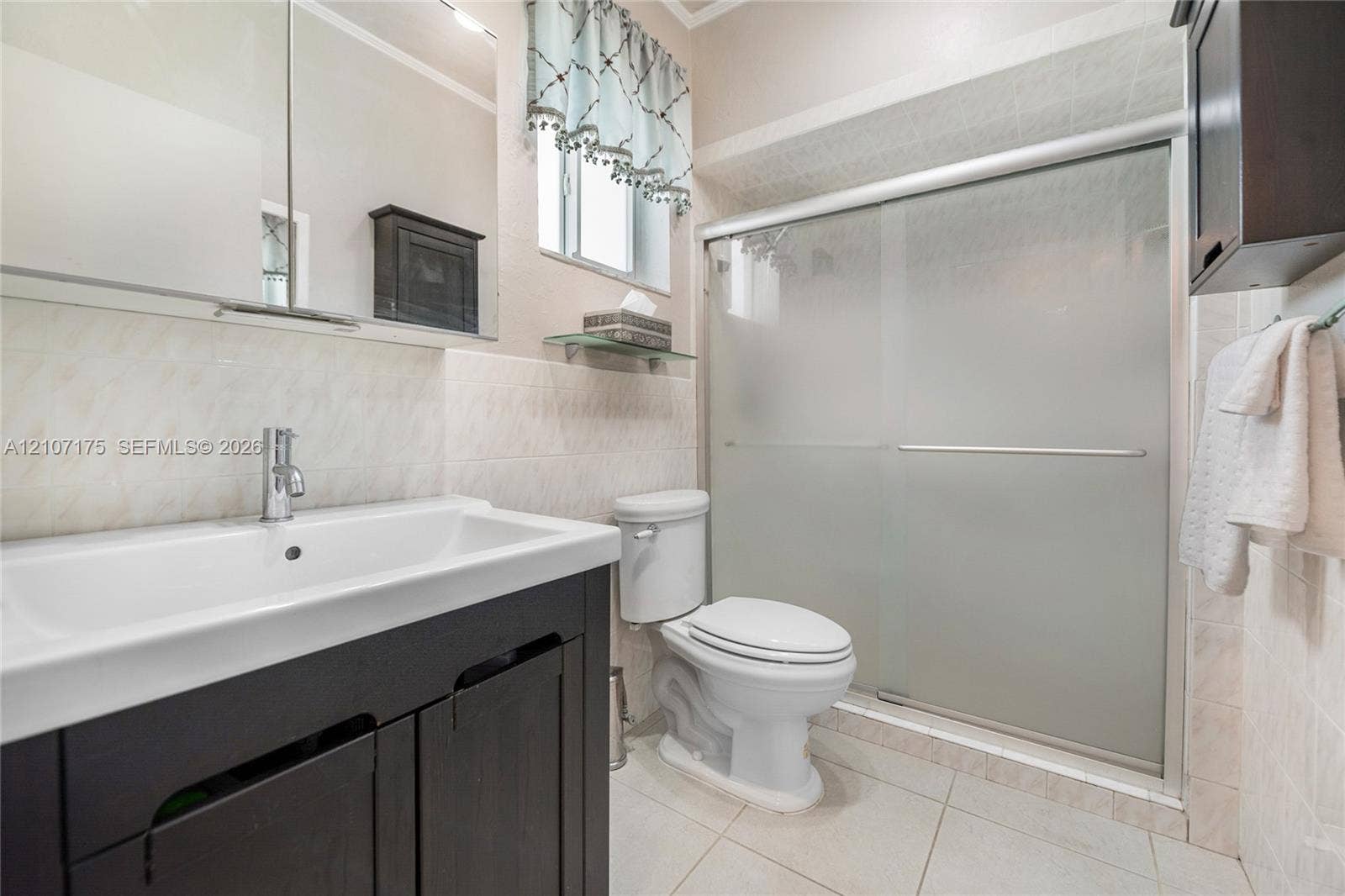 17550 SW 86th Avenue, Palmetto Bay, FL 33157 4th Bedroom En-Suite Bath. Dark wood-finish vanity with a rectangular sink, polished chrome faucet, tile-surround shower with frosted sliding glass doors.