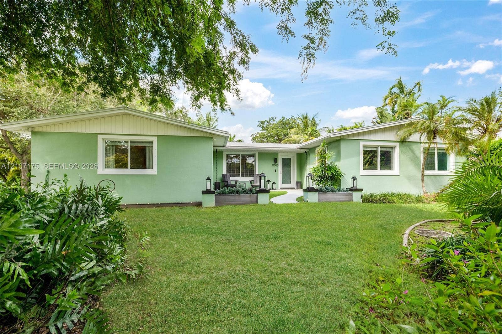 17550 SW 86th Avenue, Palmetto Bay, FL 33157 Single-story exterior featuring expansive manicured lawn, integrated concrete planters, and a paved walkway.