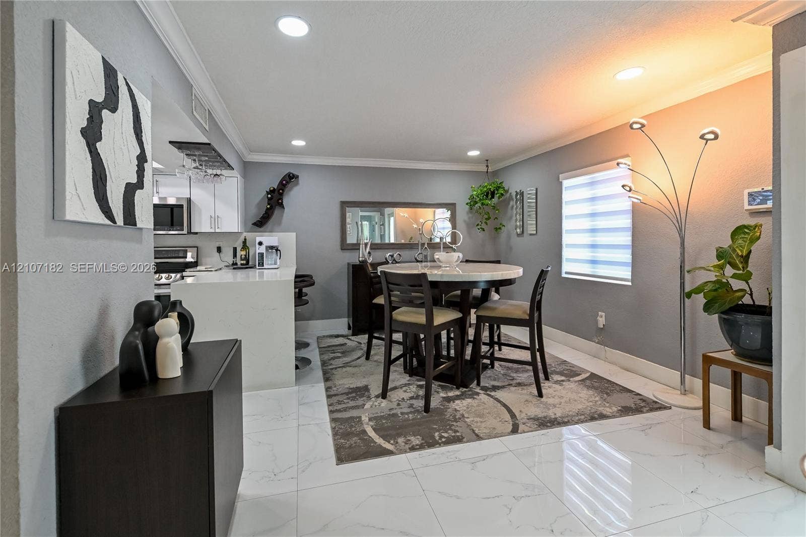 Large-format tile flooring, recessed lighting, crown molding, and a kitchen island with a light-toned countertop