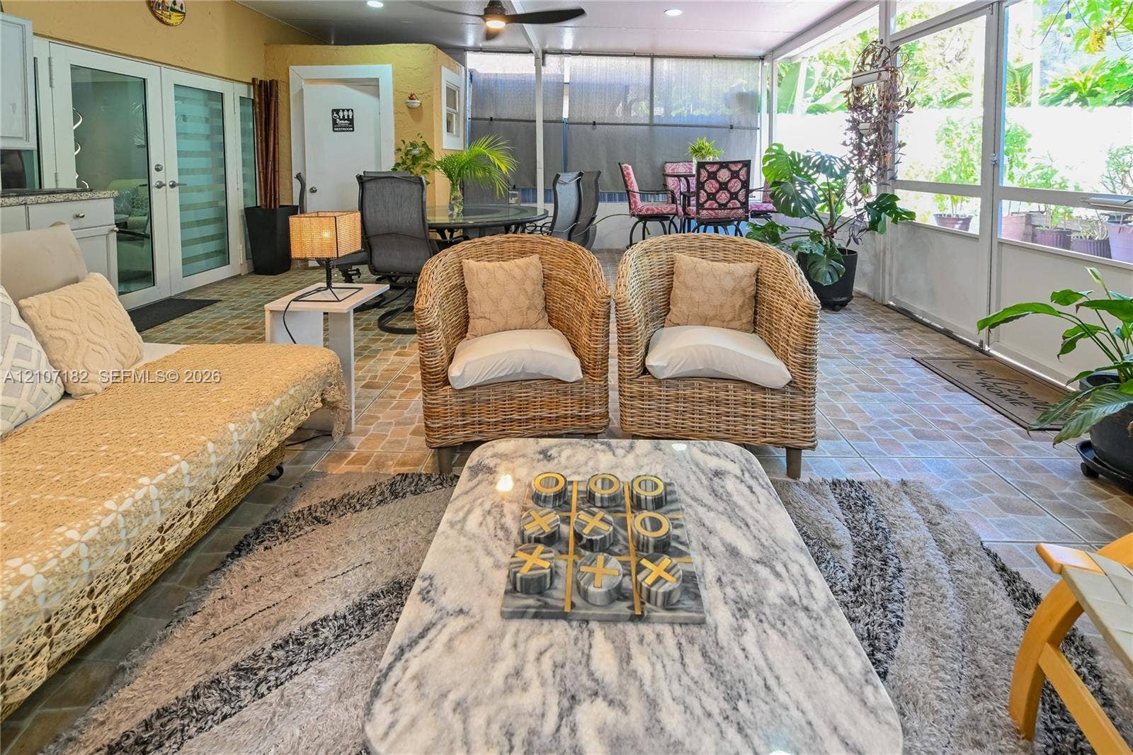 Screened-in patio featuring patterned tile flooring, ceiling fan, and double glass-pane doors