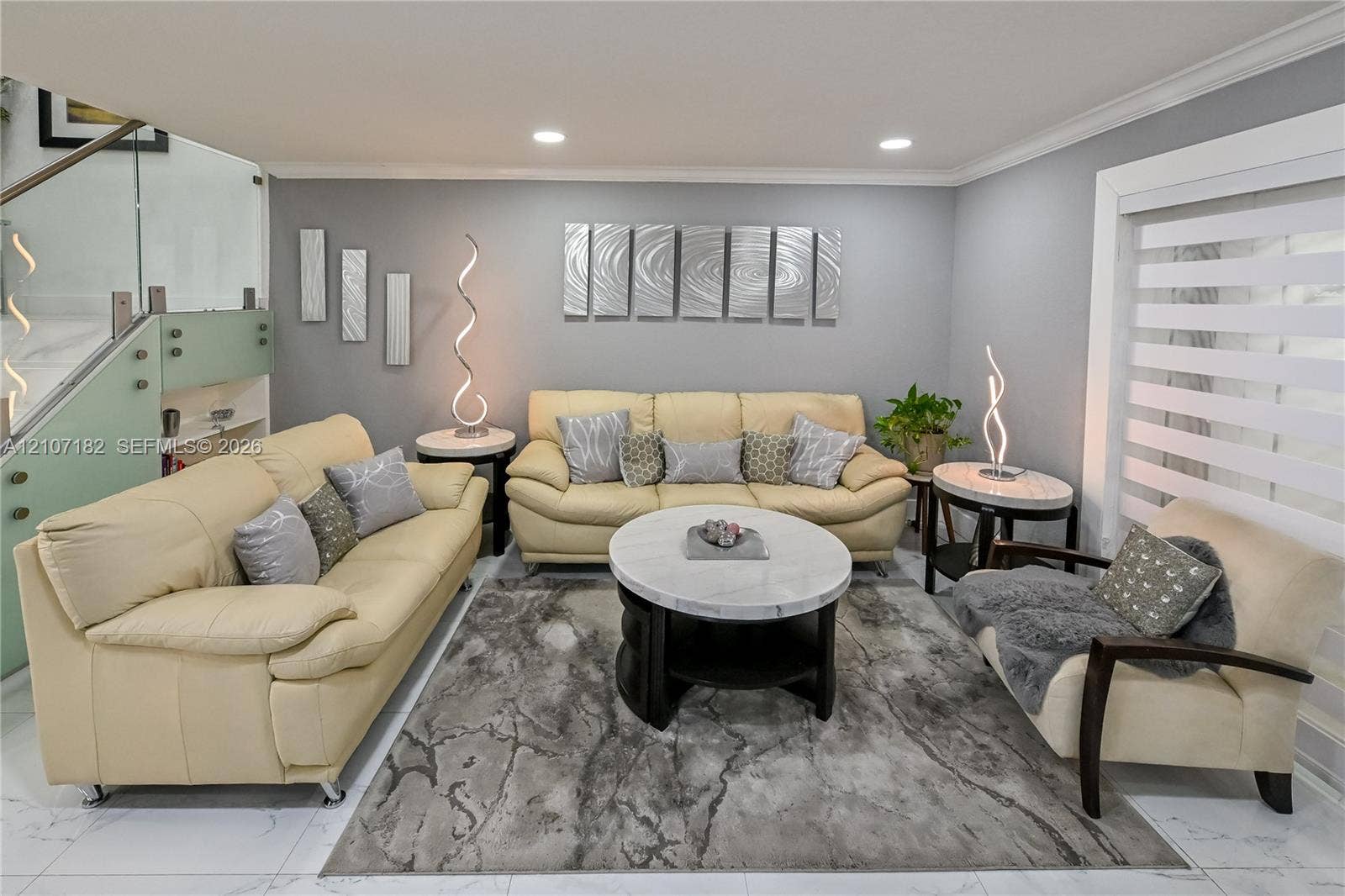 Living area featuring polished tile flooring, recessed lighting, and a staircase with glass panel railing