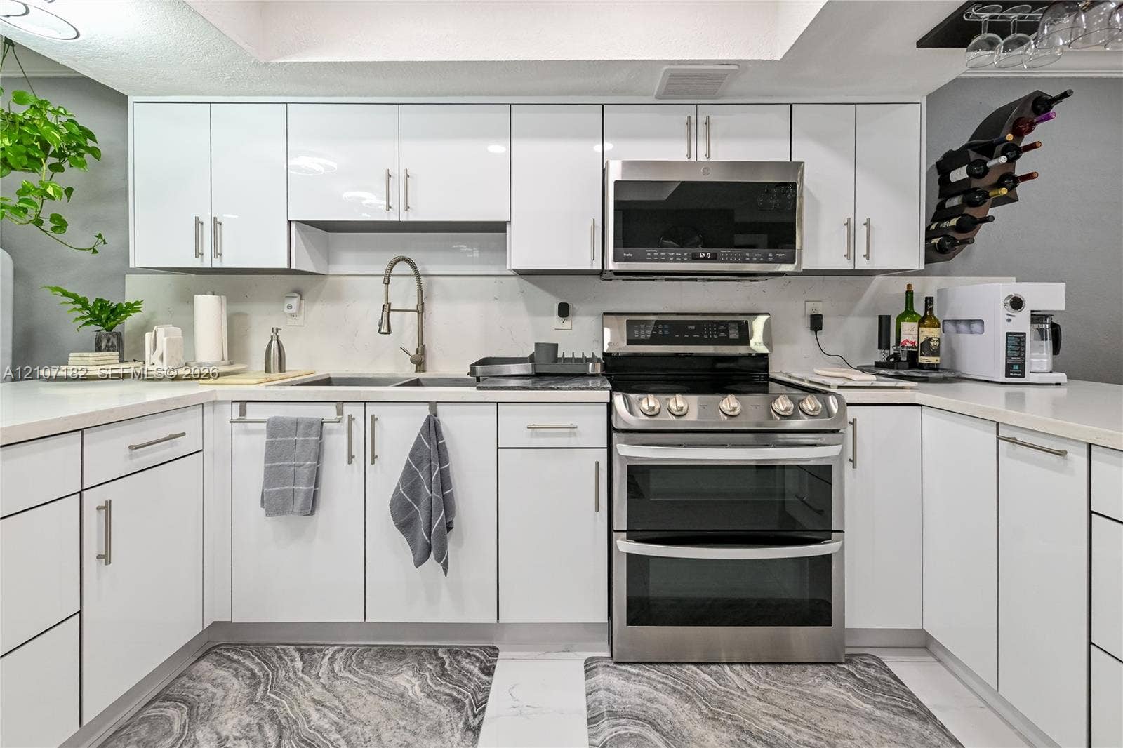 Kitchen featuring high-gloss white cabinetry, white countertops, stainless steel dual-oven range, over-the-range microwave, and a gooseneck faucet