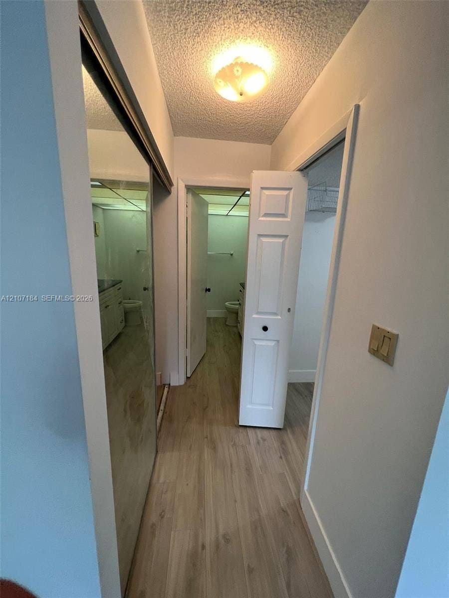 240 Lakeview Drive, #209, Weston, Weston, FL 33326 Hallway featuring wood-finish flooring, mirrored sliding closet doors, and flush-mount ceiling lighting