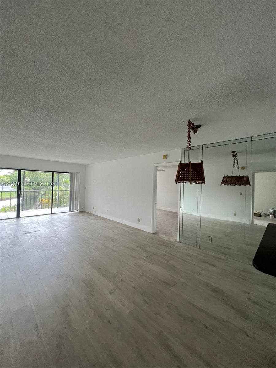 240 Lakeview Drive, #209, Weston, Weston, FL 33326 Interior space featuring wood-finish flooring, floor-to-ceiling mirrored wall panels, and glass sliding doors with access to an exterior balcony