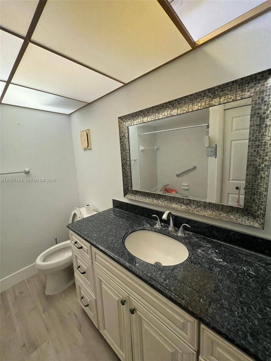 240 Lakeview Drive, #209, Weston, Weston, FL 33326 Bathroom featuring a stone vanity countertop with an integrated undermount sink, white cabinetry with dark hardware, a framed mosaic tile mirror, and recessed grid ceiling lighting