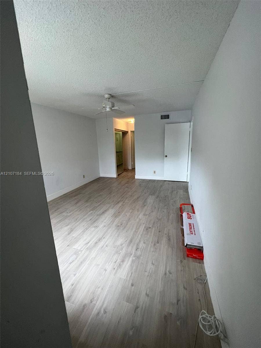 240 Lakeview Drive, #209, Weston, Weston, FL 33326 Interior space featuring wood-finish flooring, white walls, and a ceiling-mounted fan with integrated light fixture