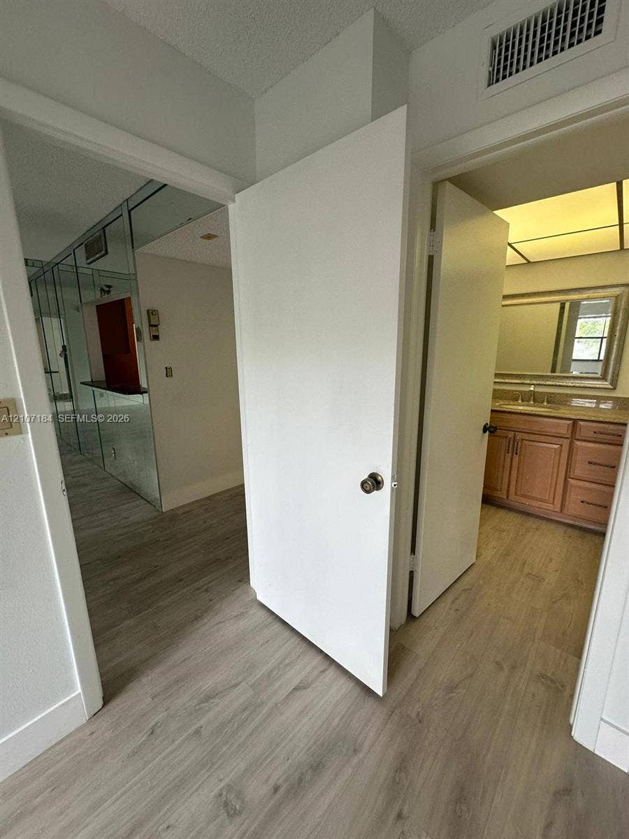 240 Lakeview Drive, #209, Weston, Weston, FL 33326 Wood-finish flooring throughout, vanity with stone countertop and framed mirror, and floor-to-ceiling mirror panels