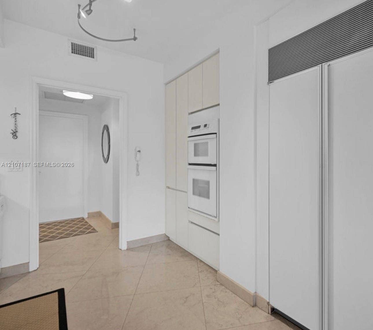 9601 Collins Avenue, #403, Bal Harbour, FL 33154 Built-in floor-to-ceiling cabinetry, integrated white double wall ovens, panel-ready full-height refrigerator, and stone-finish floor tile