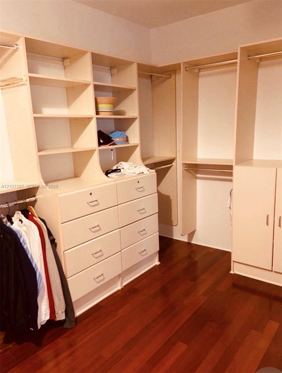 9601 Collins Avenue, #403, Bal Harbour, FL 33154 Customized walk-in closet featuring floor-to-ceiling built-in cabinetry, eight integrated storage drawers, adjustable shelving units, dual hanging rods, and wood-finish flooring