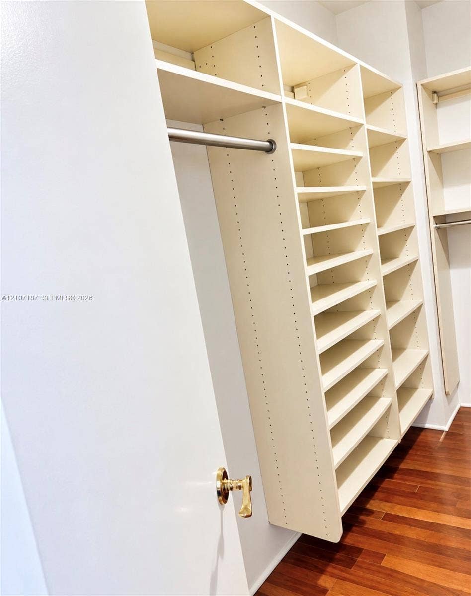 9601 Collins Avenue, #403, Bal Harbour, FL 33154 Custom walk-in closet featuring extensive built-in shelving, vertical storage partitions, integrated hanging rods, and wood-finish flooring